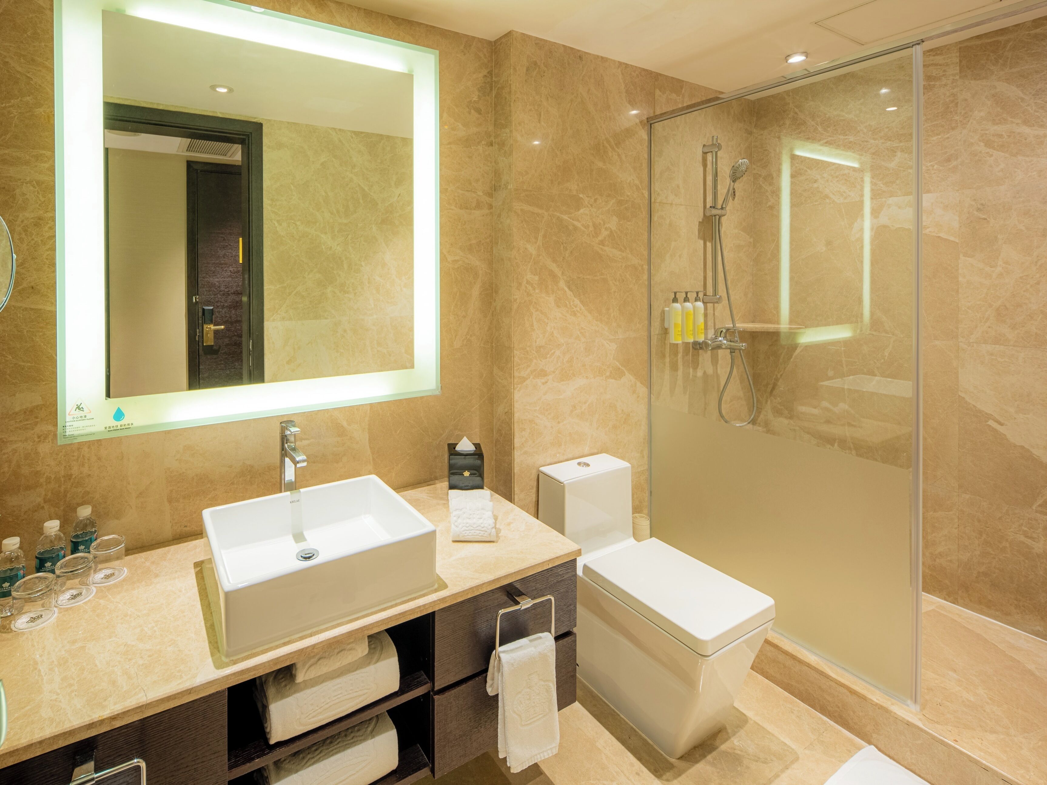 A modern bathroom with a large mirror, a sink, a toilet, and a glass-enclosed shower area.