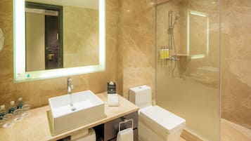 A modern bathroom with a large mirror, a sink, a toilet, and a glass-enclosed shower area.