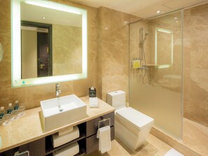 A modern bathroom with a large mirror, a sink, a toilet, and a glass-enclosed shower area. - Grand Emperor Hotel  (Macau)