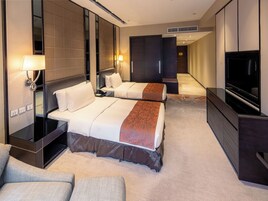 Habitación de hotel con dos camas, televisor, escritorio y silla.