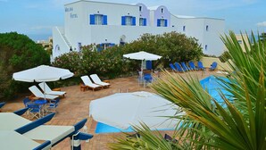A hotel with a pool area, including lounge chairs and umbrellas, and a building with blue shutters. - Melina Hotel (Santorini)
