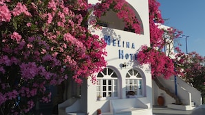 A white building with the name "MELINA HOTEL" in blue letters. - Melina Hotel (Santorini)
