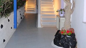A narrow pathway leading to a staircase with a tree and flowers on the right. - Melina Hotel (Santorini)