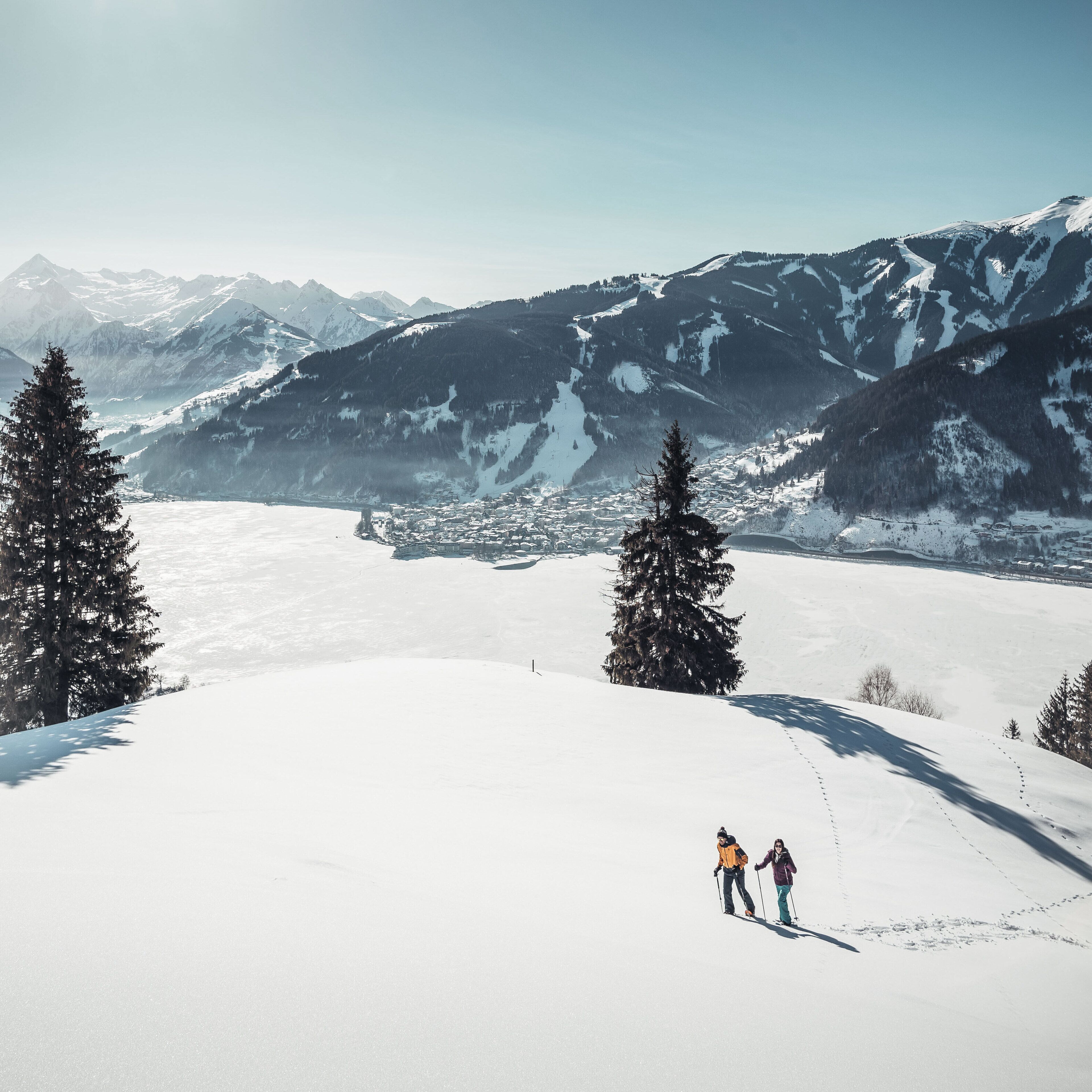 A snowy mountain landscape with two skiers.