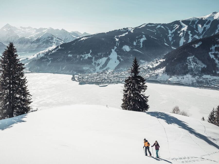 A snowy mountain landscape with two skiers.