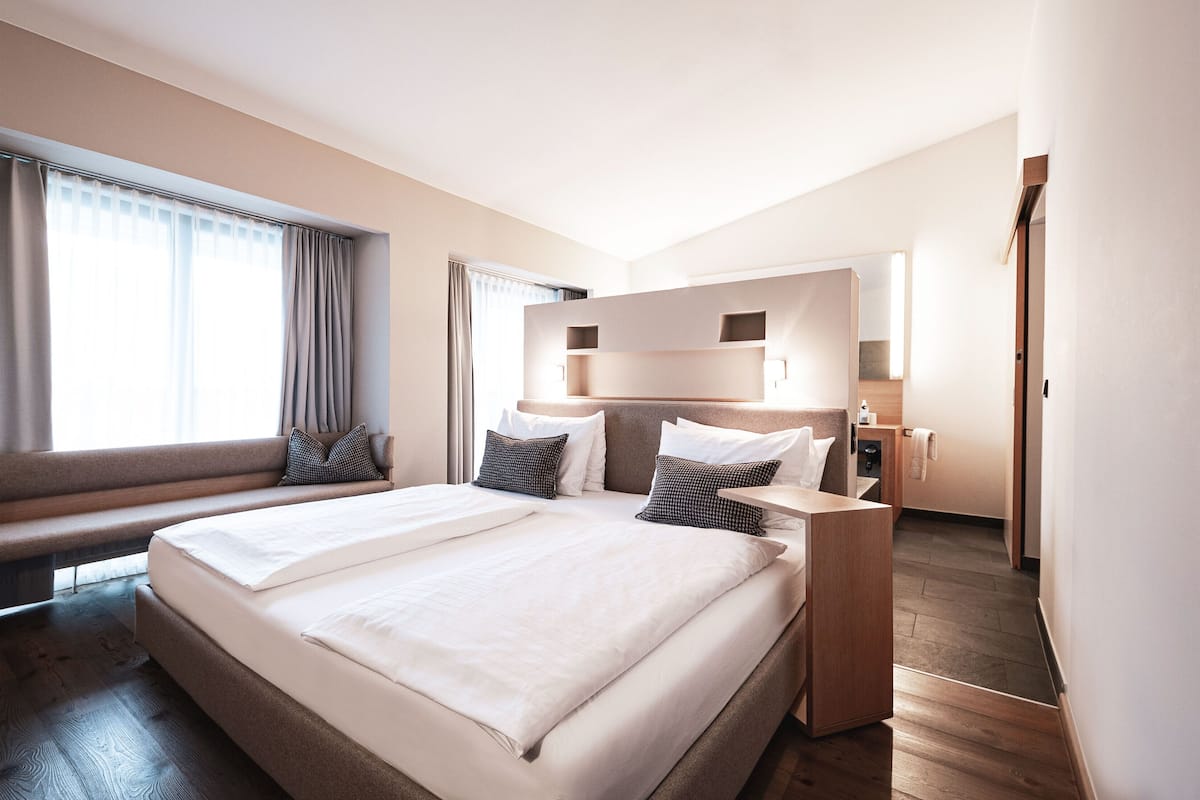 Ett modernt hotellrum med en stor säng, en bänk och ett skrivbord.