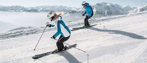 Une piste de ski enneigée avec deux skieurs en mouvement.