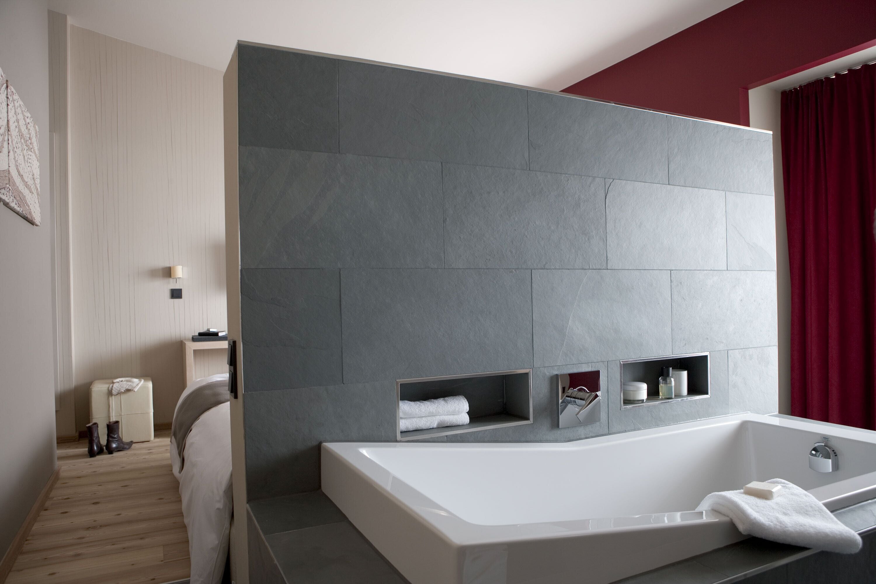 A modern bathroom with a large bathtub, built-in shelves, and a wooden floor.