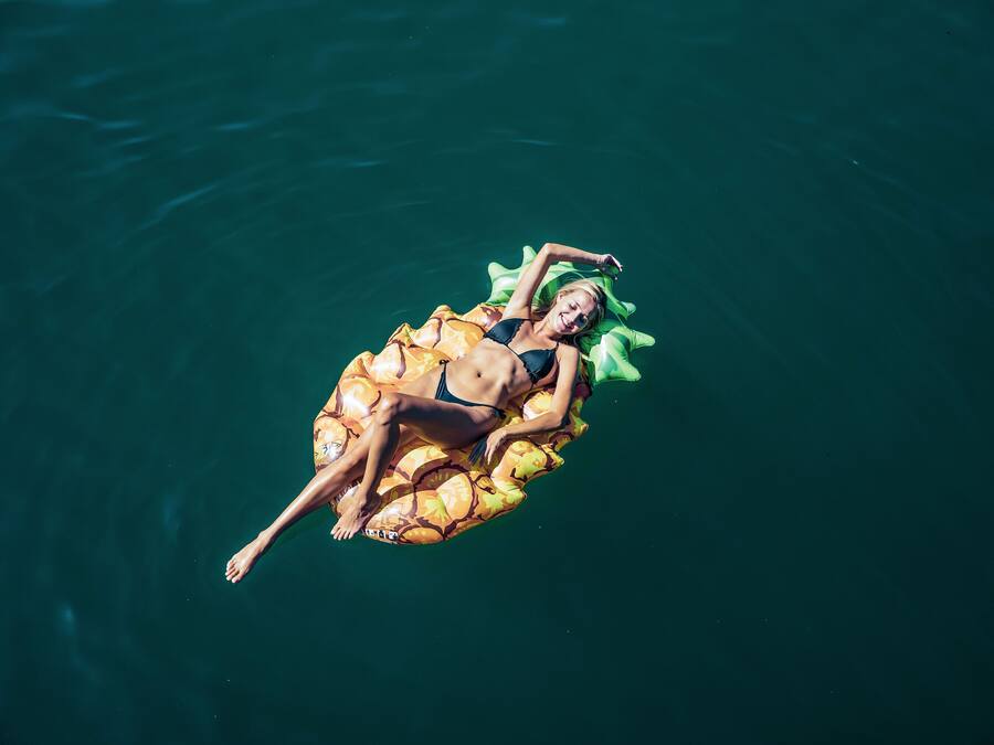 A person floating on a water body using an inflatable raft.