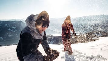 Dos personas en una montaña nevada con vistas despejadas a montañas distantes y un valle.