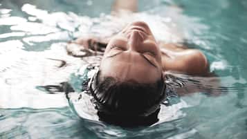 A person lying on their back in a swimming pool.