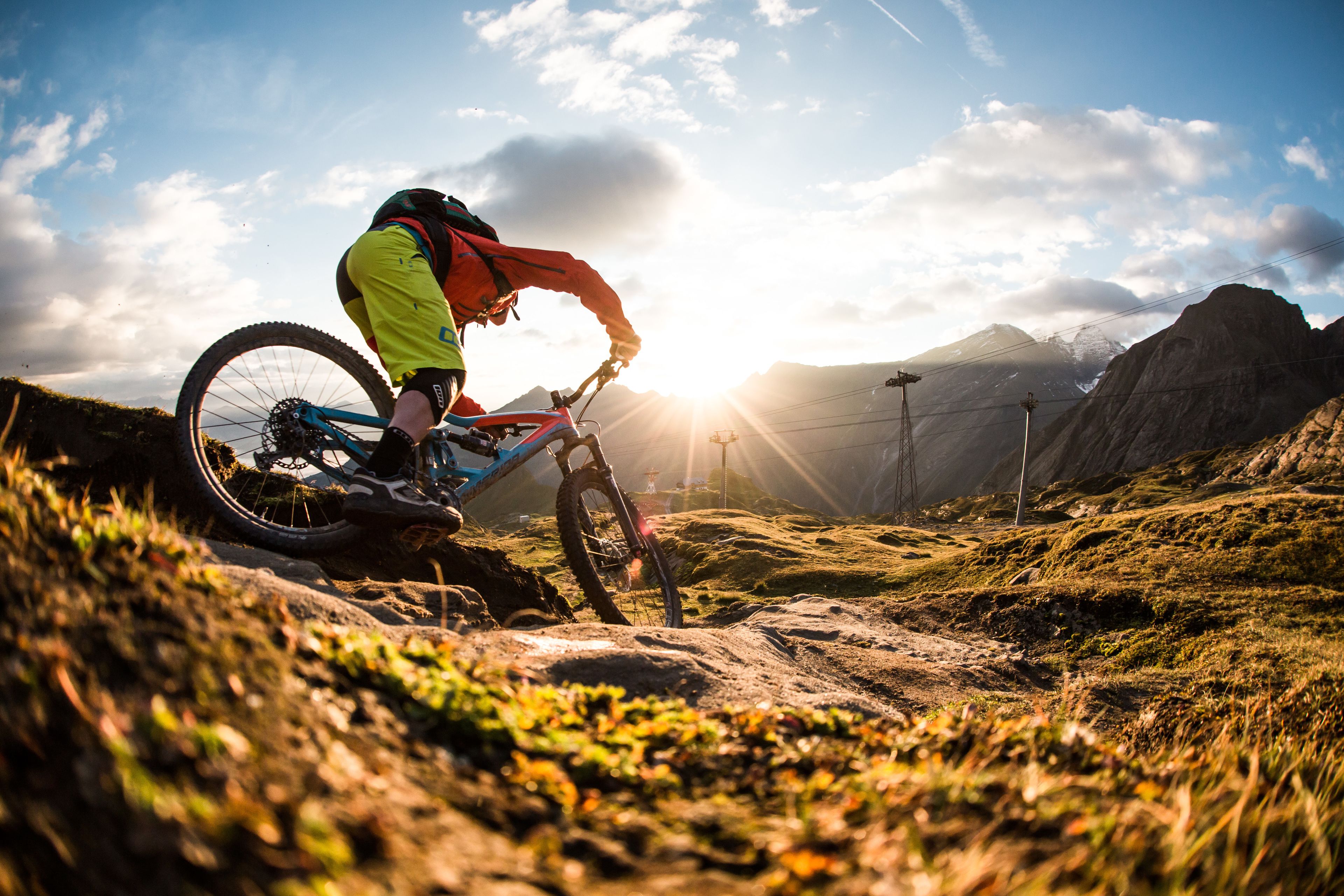 A mountain biker on a trail with a clear sky and distant mountains.