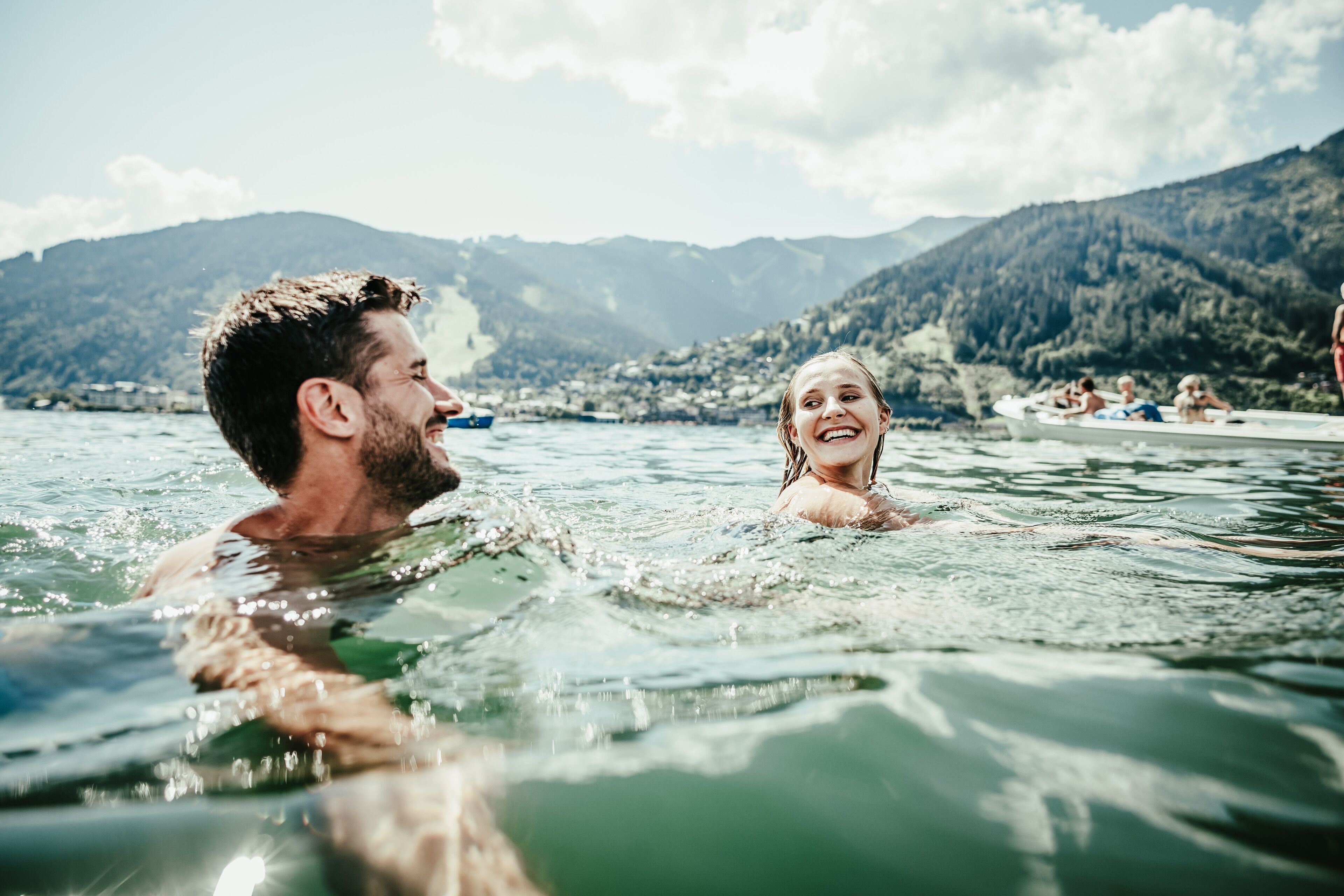 Una pareja en el agua, con un paisaje montañoso al fondo.
