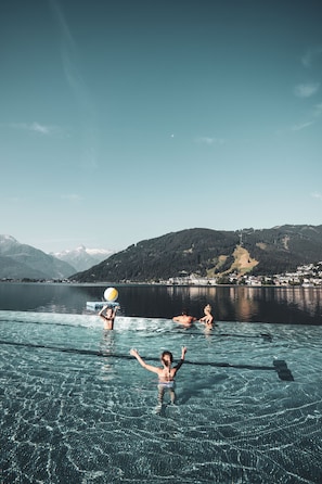 A clear view of a lake with mountains in the background, a boat, and people in the water.