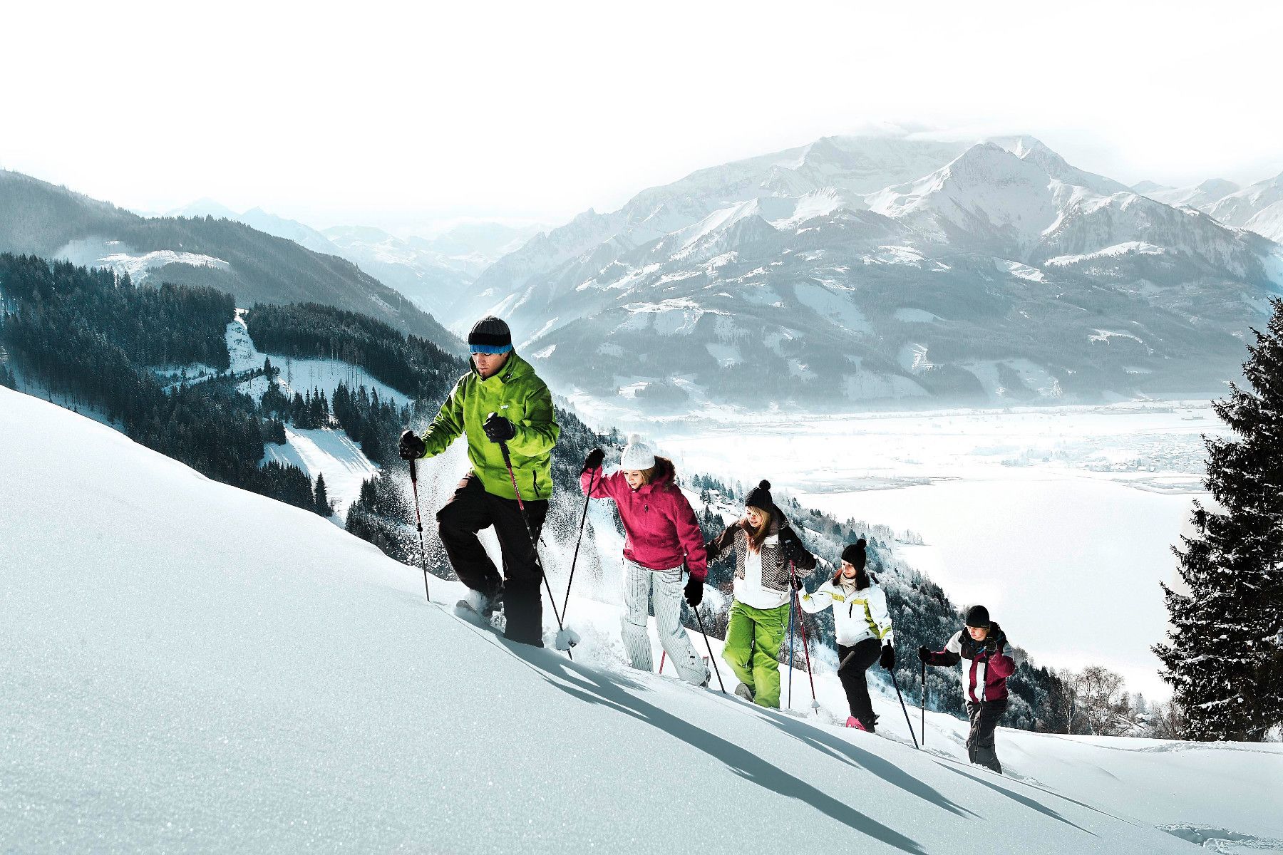 Een groep mensen skiënd een besneeuwde helling, met een bergachtige achtergrond.