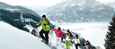 Een groep mensen skiënd een besneeuwde helling, met een bergachtige achtergrond.