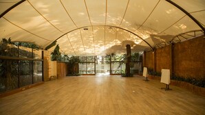 Un espacio interior amplio con suelo de madera, ventanas grandes y un techo alto con un dosel translúcido.
