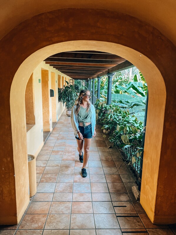 A corridor with arches, tiled flooring, and potted plants. - Hotel Las Farolas (Antigua Guatemala)