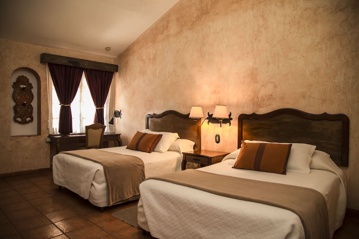 Una habitación de hotel con dos camas, un escritorio y una silla.