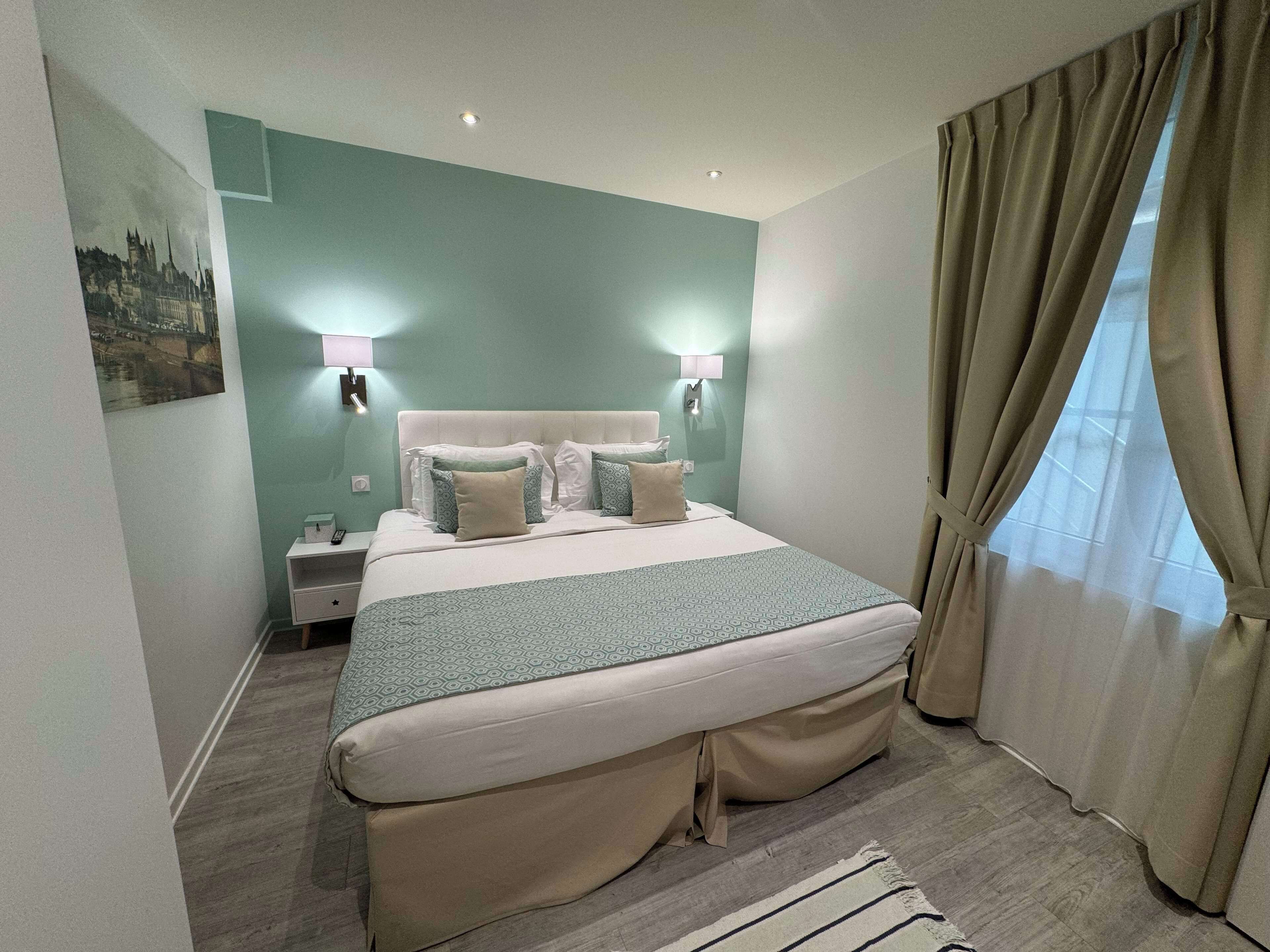 Ein ordentlich eingerichtetes Schlafzimmer mit einem großen Bett, zwei Nachttischen und einem Schminktisch.