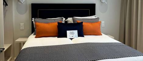 Una habitación de hotel con una cama grande, dos mesitas de noche, un armario y una lámpara en el techo.
