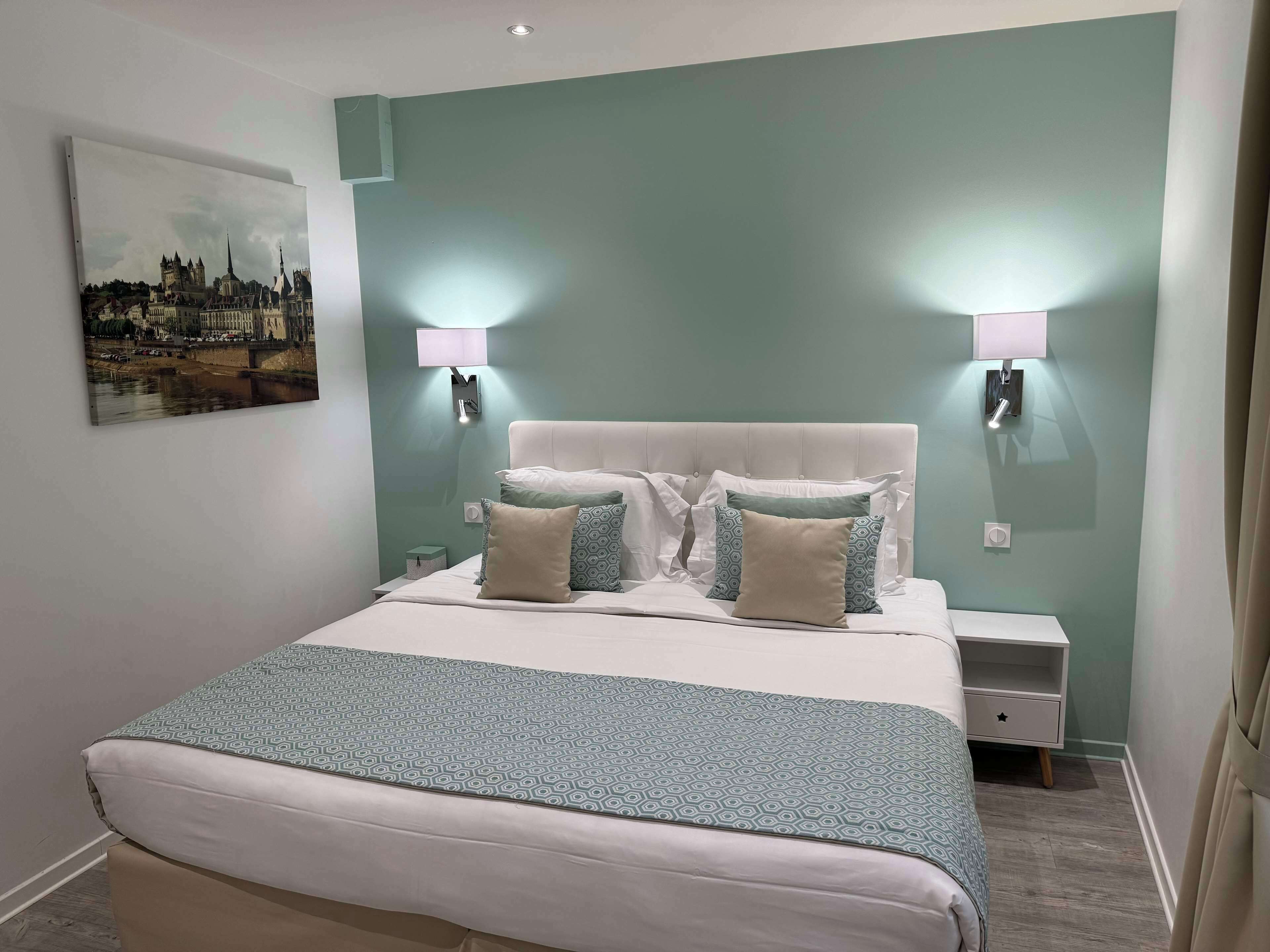Un dormitorio ordenado con cama, dos mesitas de noche y una lámpara de pared.