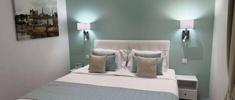 Un dormitorio ordenado con cama, dos mesitas de noche y una lámpara de pared.