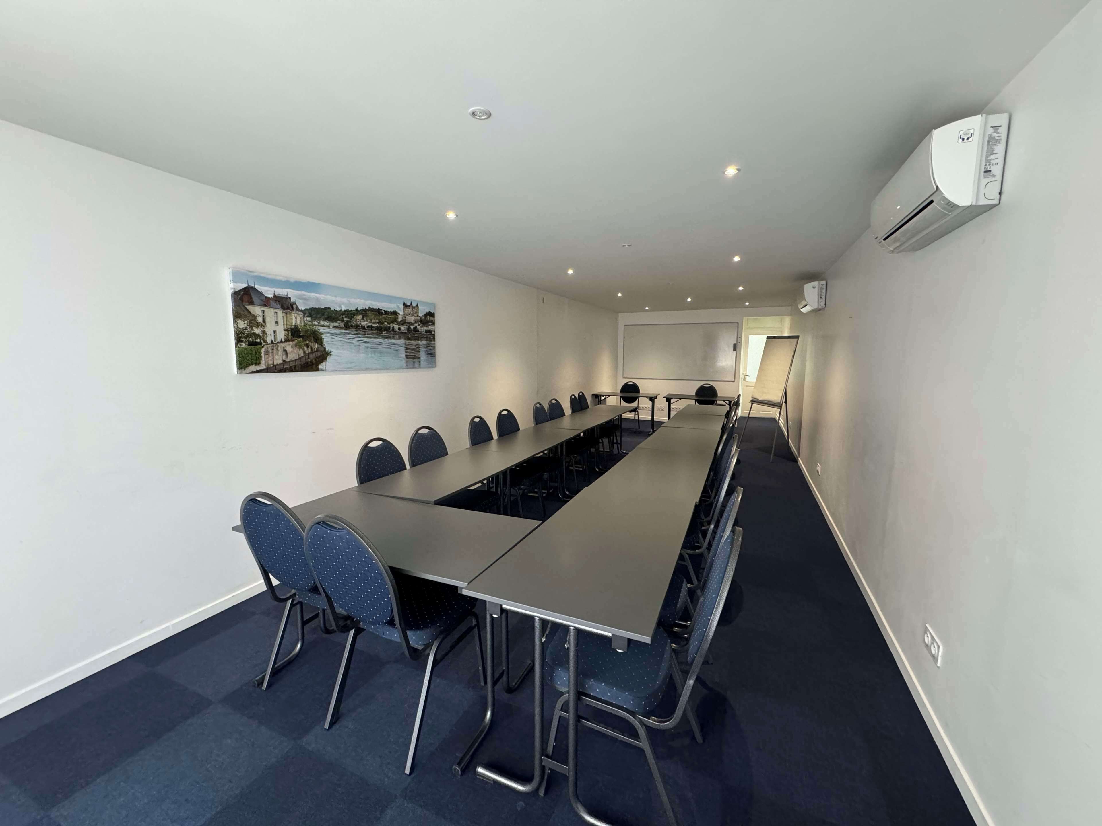 A conference room with a long table, chairs, a whiteboard, and an air conditioning unit.