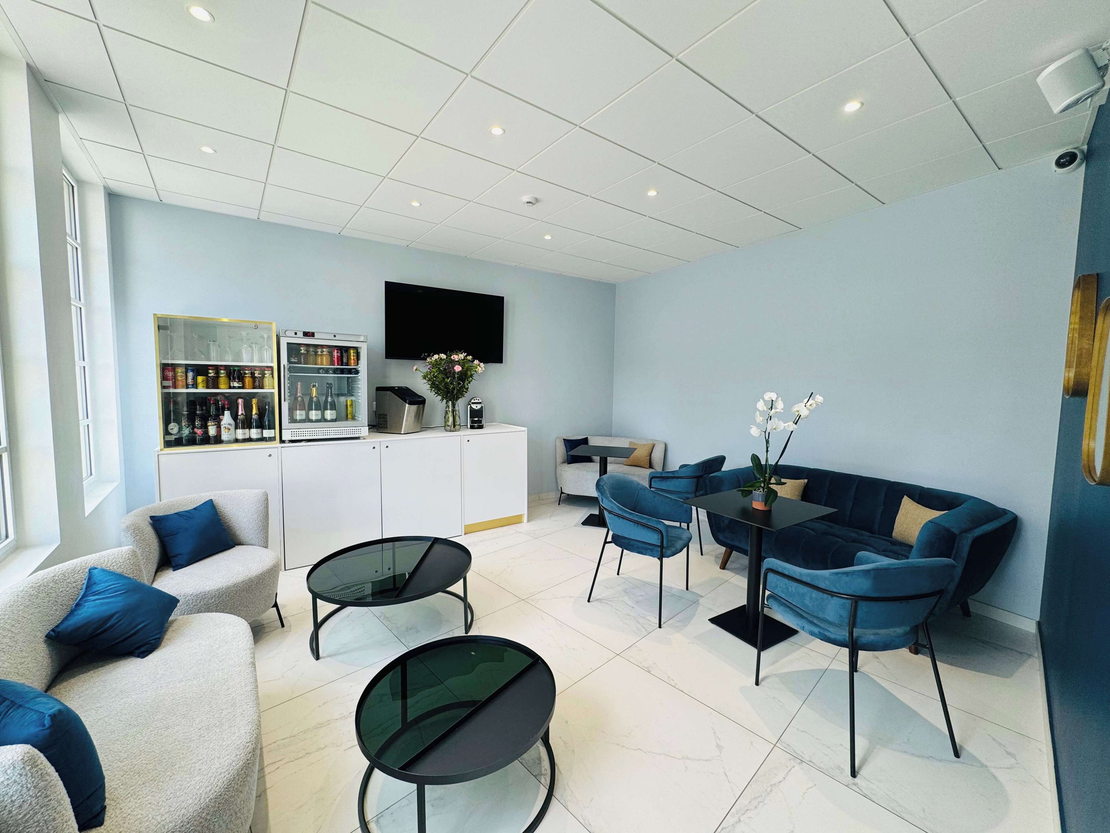 A modern living room with a sofa, two armchairs, a coffee table, and a TV mounted on the wall.