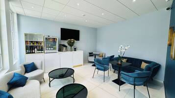 A modern living room with a sofa, two armchairs, a coffee table, and a TV mounted on the wall.