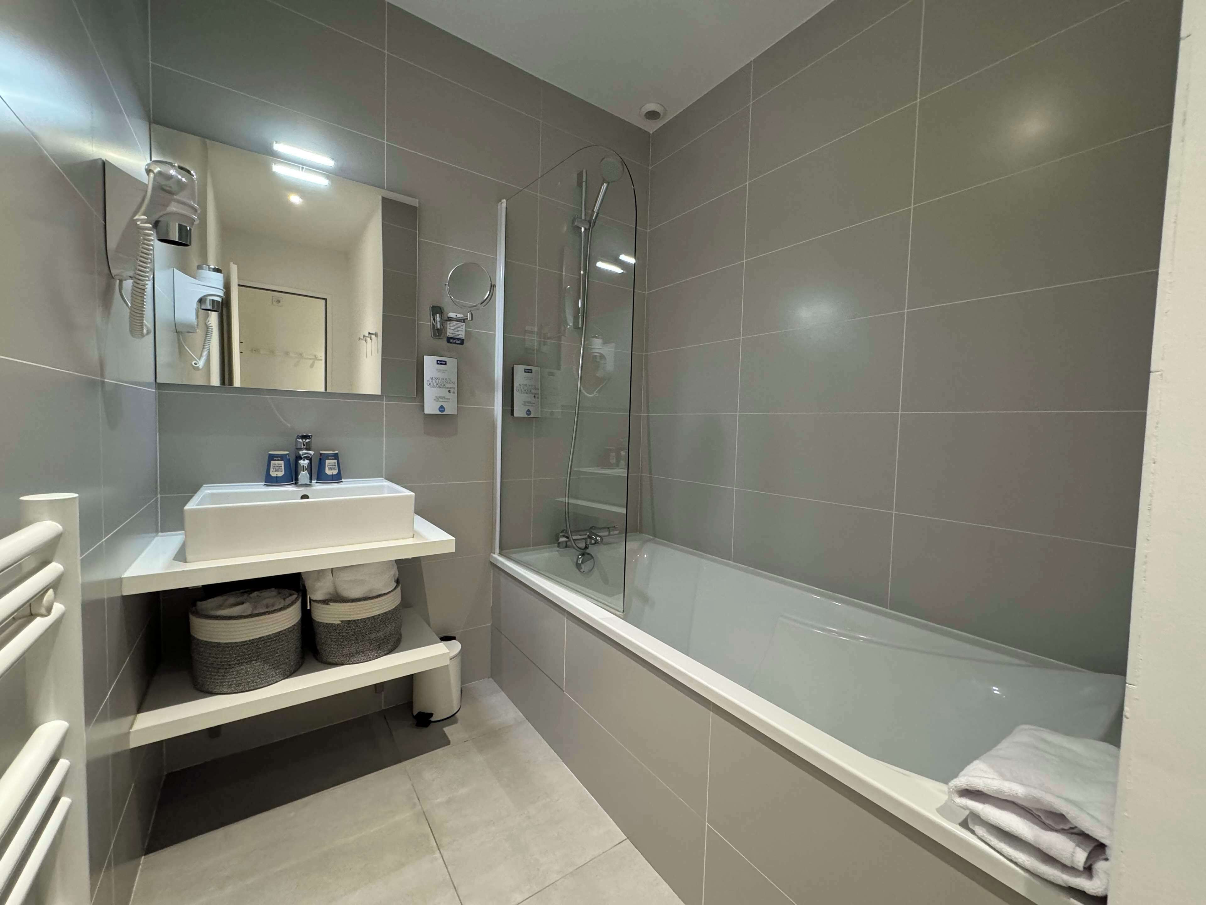 Un baño moderno con un lavamanos blanco, ducha con mampara de vidrio y bañera.