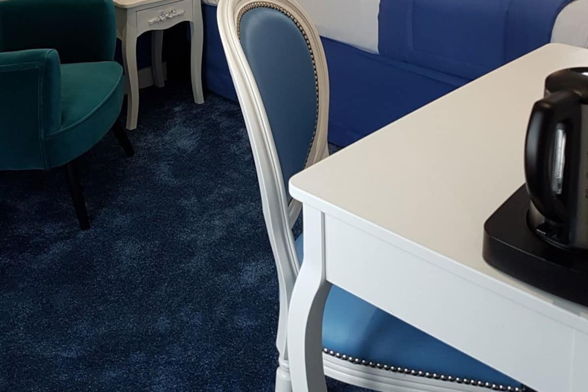 A hotel room with a large bed, a desk, a chair, and a table.