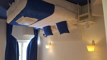 Een kamer met een stapelbed, een raam met gordijnen en wandlampen.