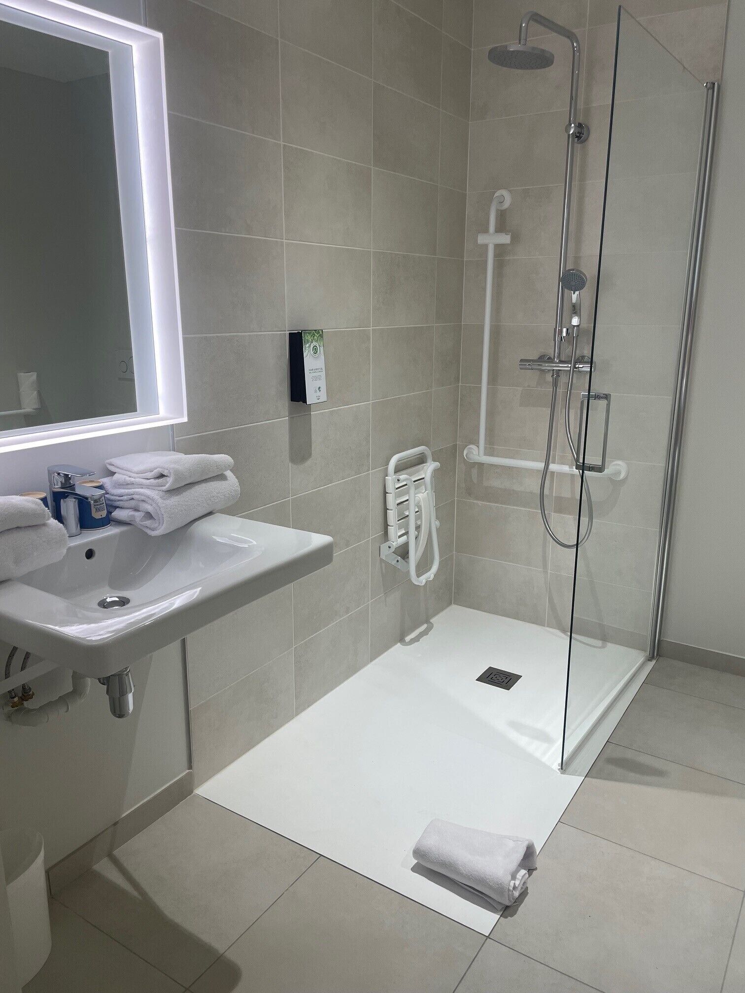 A modern bathroom with a white sink, mirror, and glass shower enclosure.