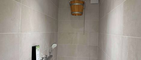 A shower with a wooden bucket, a handheld showerhead, and a wall-mounted control panel.
