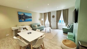 Una sala de estar moderna con comedor, un sofá, un televisor y un cuadro en la pared.