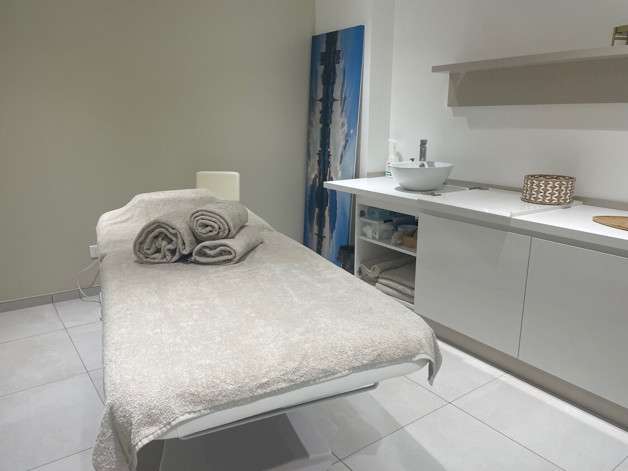 A clean, modern room with a bed, a sink, and a towel rack.