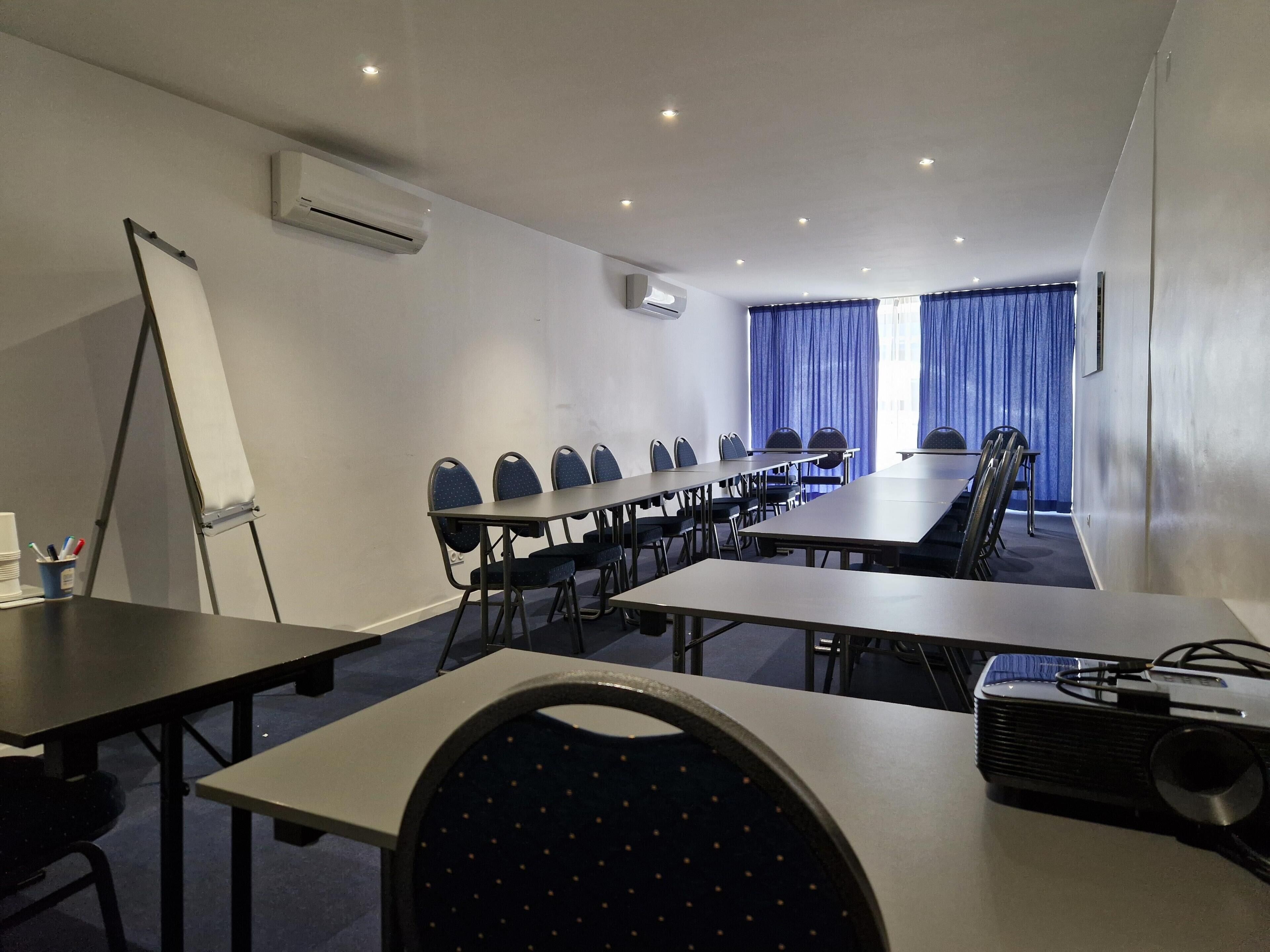 A conference room with a whiteboard, projector, and rows of chairs.