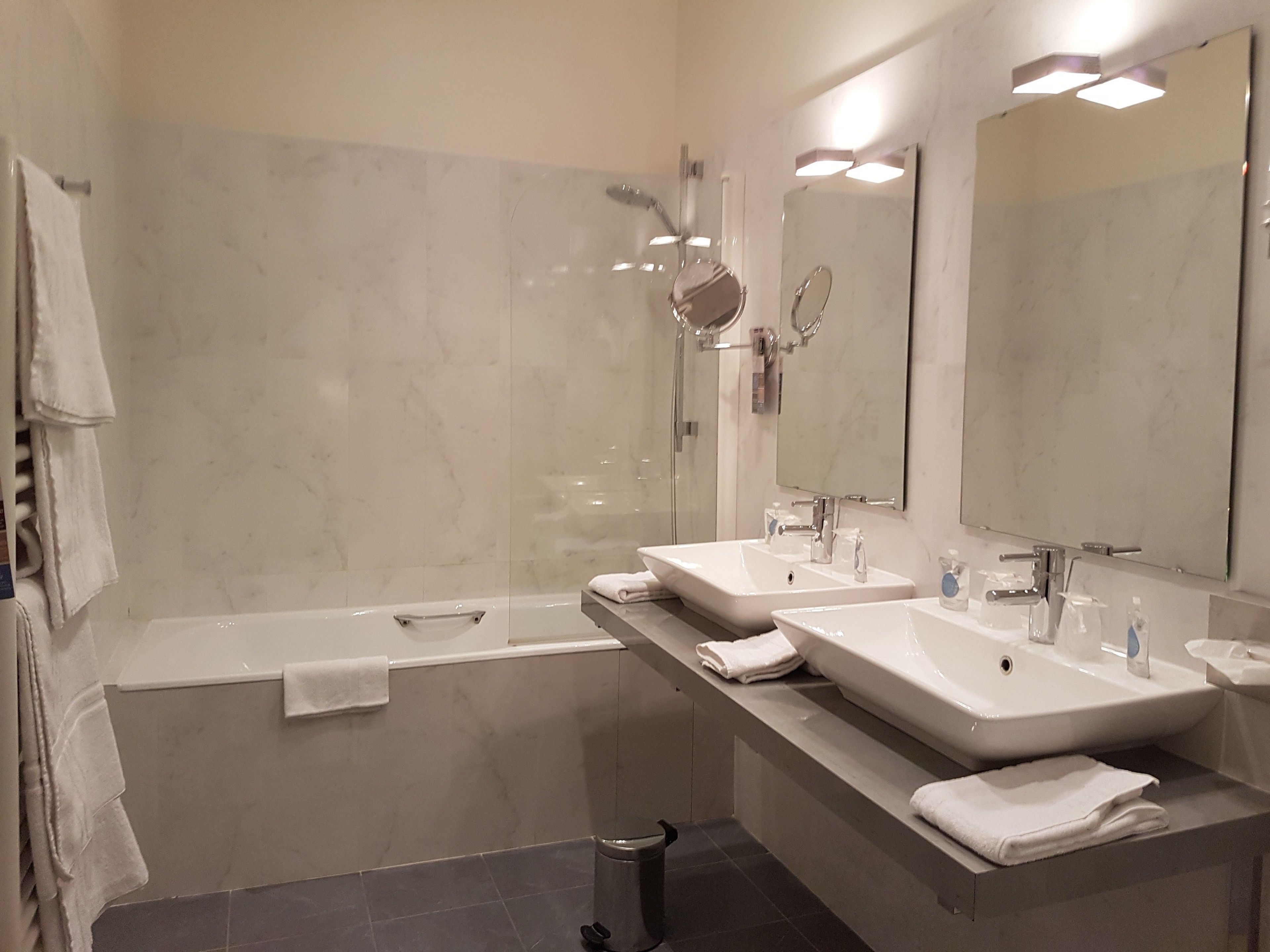 A modern bathroom with a bathtub, two sinks, and a large mirror.