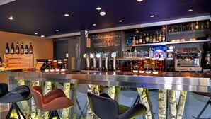 A bar area with stools, a counter, and various bottles and glasses. - Kyriad La Roche Sur Yon (La Roche-sur-Yon)