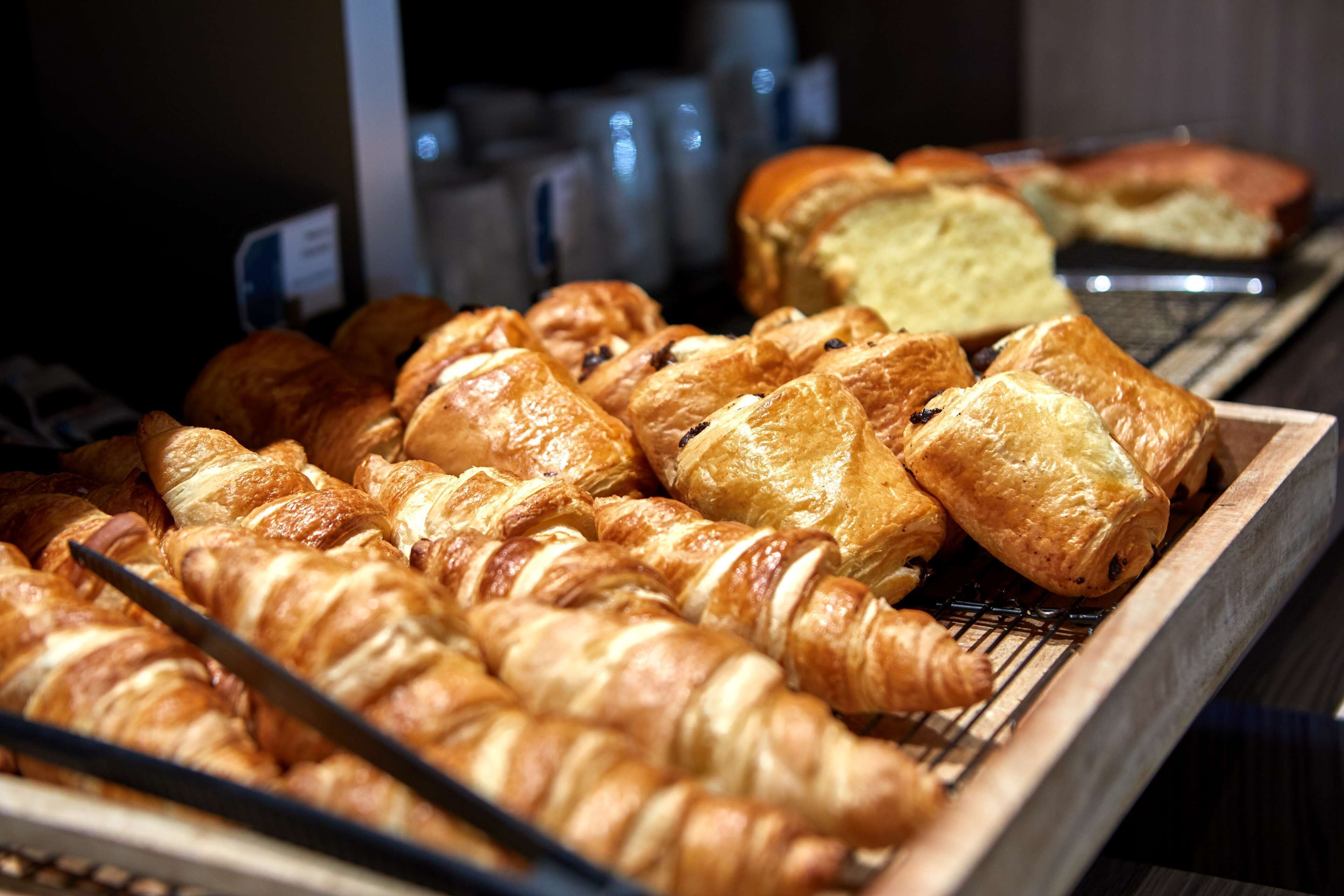 A display of various baked goods, including croissants and bread, in a bakery setting.