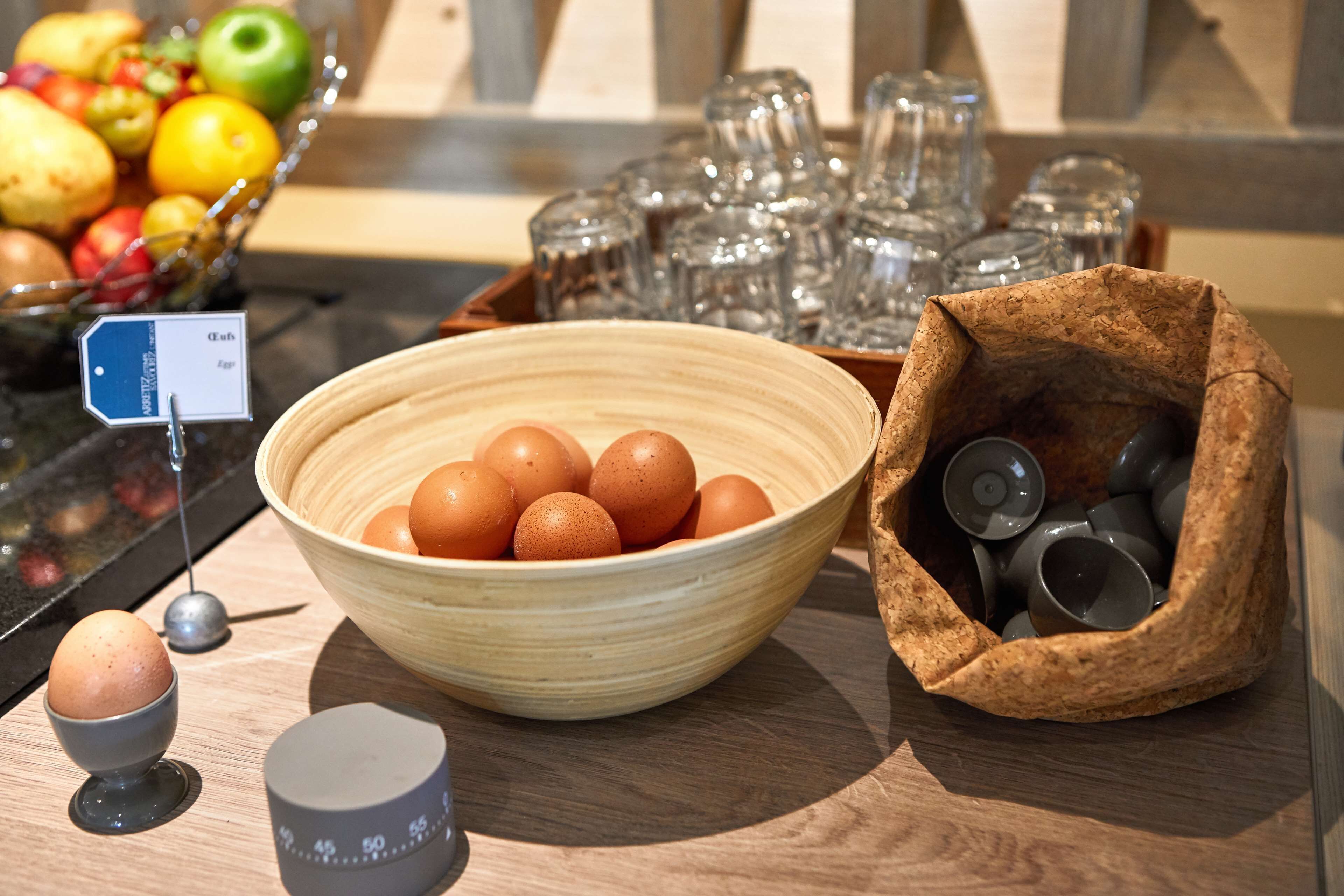 A kitchen counter with a bowl of eggs, a salt shaker, and a basket of fruits.