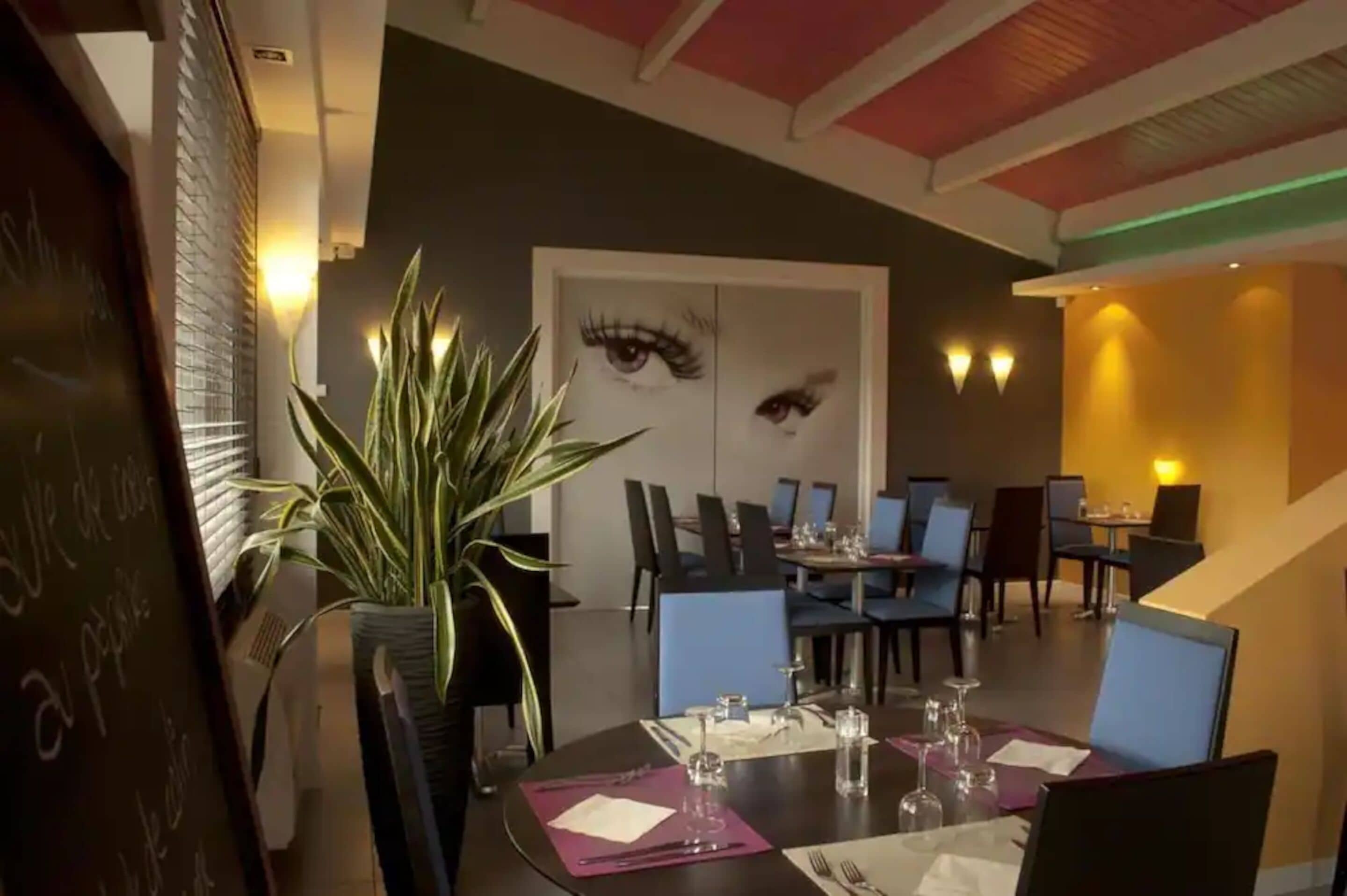 A dining area with tables set for two, chairs, and a potted plant.