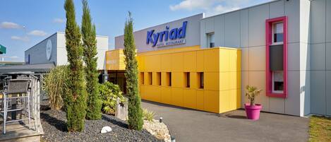 A modern building with a prominent "Kyriad Hotel Restaurant" sign.