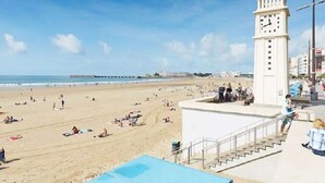 A beach with a clock tower, a pier in the distance, and people relaxing on the sand. - Kyriad La Roche Sur Yon (La Roche-sur-Yon)
