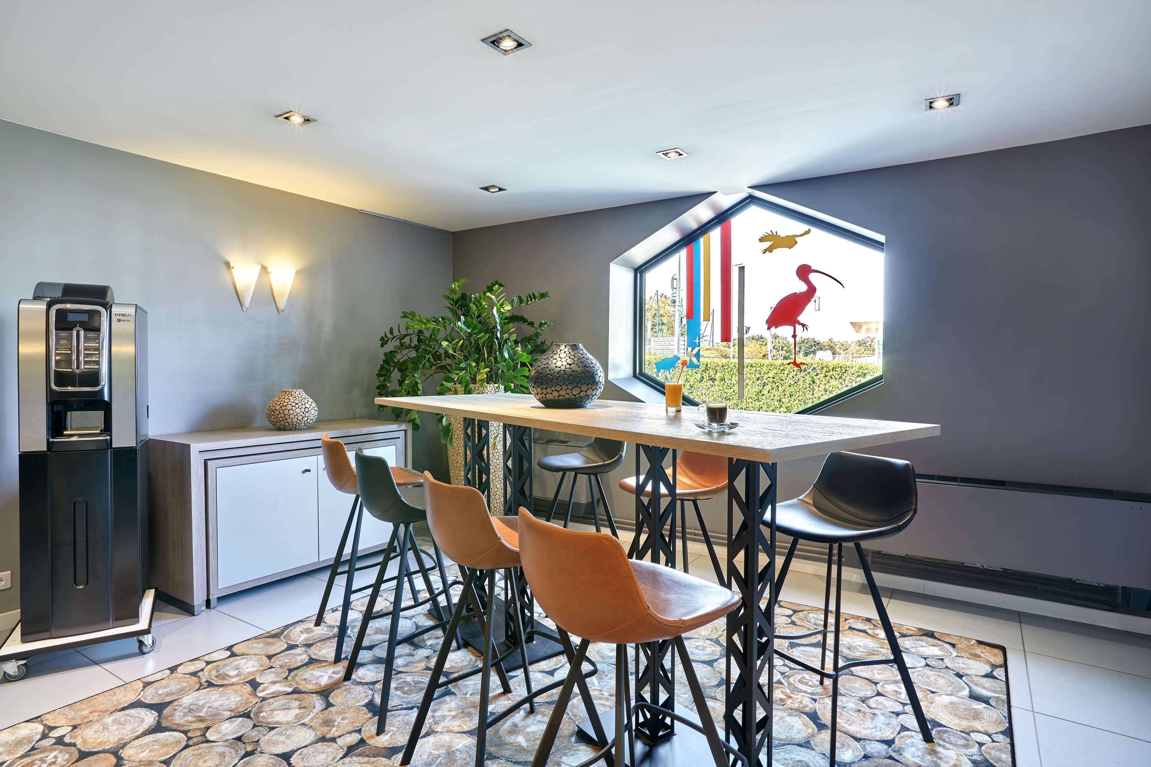 Een moderne keuken met een inbouwkoelkast, een eetgedeelte met een groot raam en een vloer met een steenmotief.