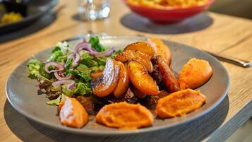 Un plato de comida con verduras asadas y una ensalada sobre una mesa de madera.