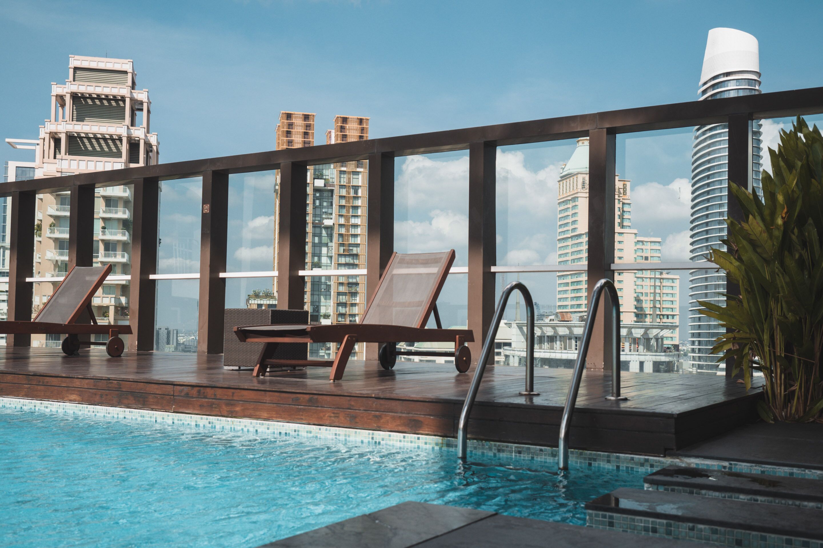 Ein Pool auf dem Dach mit Liegestühlen und Blick auf moderne Gebäude.