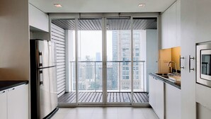 A modern kitchen with a large window, a built-in oven, and a view of high-rise buildings. - Urbana Langsuan Hotel (Bangkok)