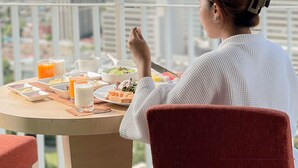A person seated at a table with breakfast items, overlooking a cityscape. - Urbana Langsuan Hotel (Bangkok)